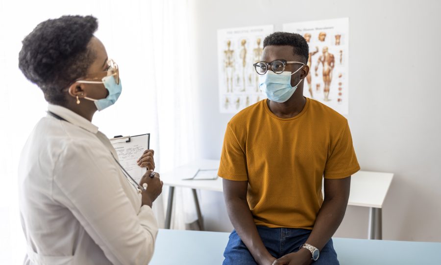 Female Adult doctor discussing with a man patient in protective medical masks medical report in hospital.